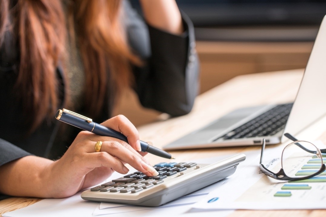 Womans Hand with Calculator Calculating Financial Benefit of Charity in Business