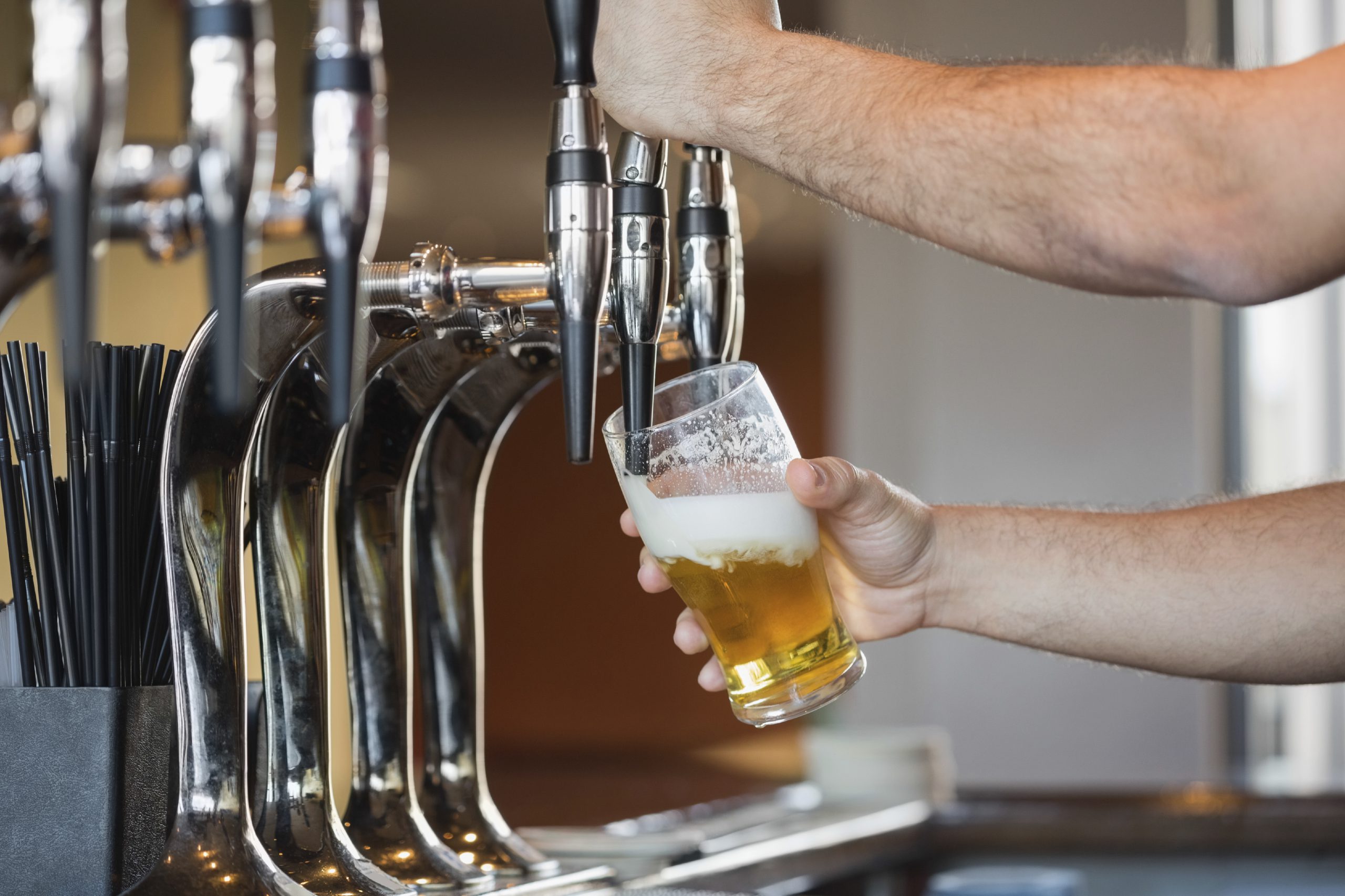 Barmans arms pulling a pint of beer behind the bar