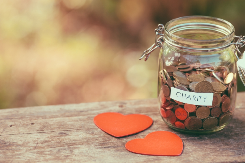 Charity Jar Filled with Coins Laying Next to Hearts